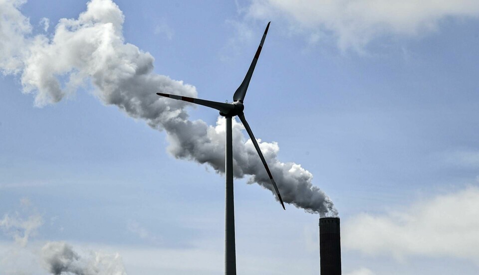 Hur måste energiproduktionen ställas om? Bild på en vindturbin och en kolkraftsskorsten i Gelsenkirchen tidigare i vår. Foto: Martin Meissner/AP/TT