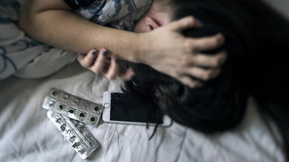 Genrebild på depression. En ung kvinna ligger i en säng med en karta tabletter bredvid sig. Foto: Stina Stjernkvist / TT