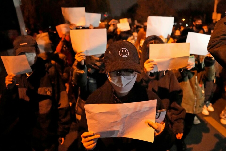 Demonstranter håller upp vita pappersark, som ska symbolisera censur, under en demonstration i Peking på söndagen. Foto: Ng Han Guan/AP/TT