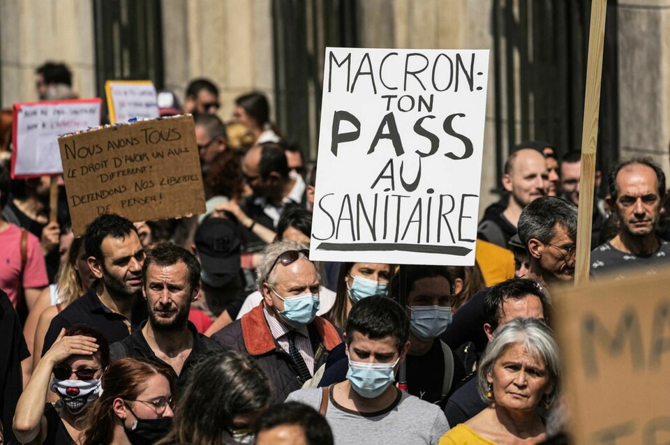 Parisdemonstranter uppmanar president Emmanuel Macron att kasta sitt hälsopass i toaletten den 17 juli. Foto: Michel Euler/AP/TT