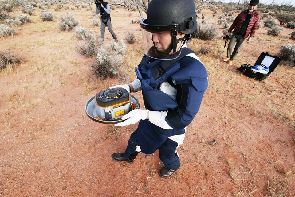 En medarbetare på Jaxa hämtar kapseln med asteroidstoft som landade i en öken i Australien. Foto: JAXA via AP/TT