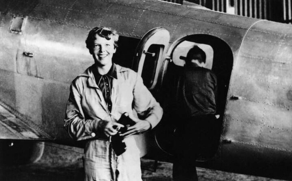 Den amerikanska piloten Amelia Earhart vid hennes Lockheed Electra. Navigatören Fred Noonan är på väg in i planet i bakgrunden. Foto: Wikipedia