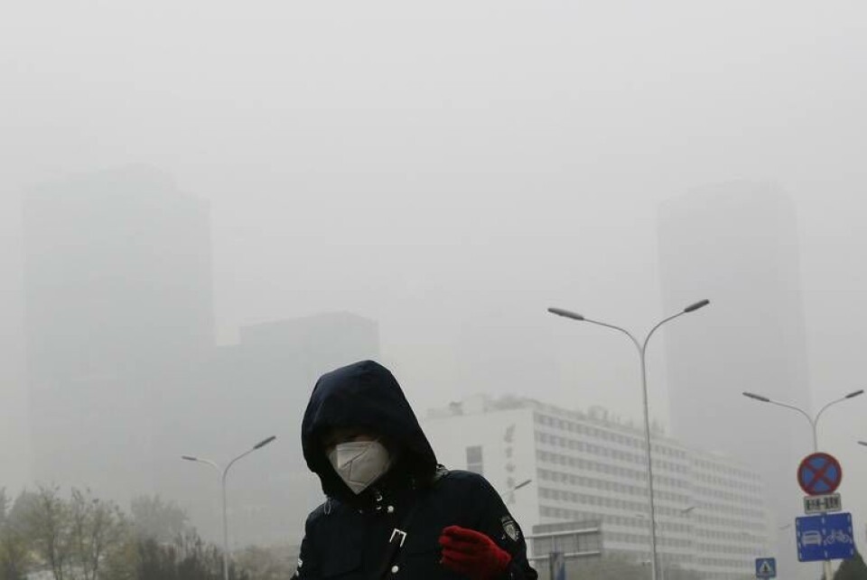En kvinna skyddar sig mot föroreningar genom att använda munskydd i Peking. Bilden är från 2018. Foto: Andy Wong/AP/TT En kvinna skyddar sig mot föroreningar genom att använda munskydd i Peking. Bilden är från 2018. Foto: Andy Wong/AP/TT