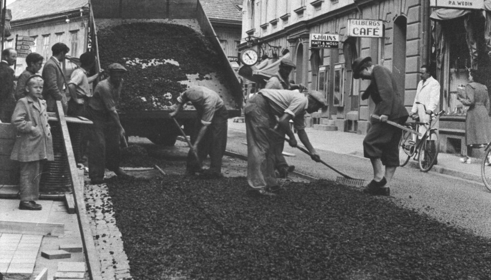 En grupp arbetare lägger betong på en central väg i Bergshammar. Bilden är svartvit.