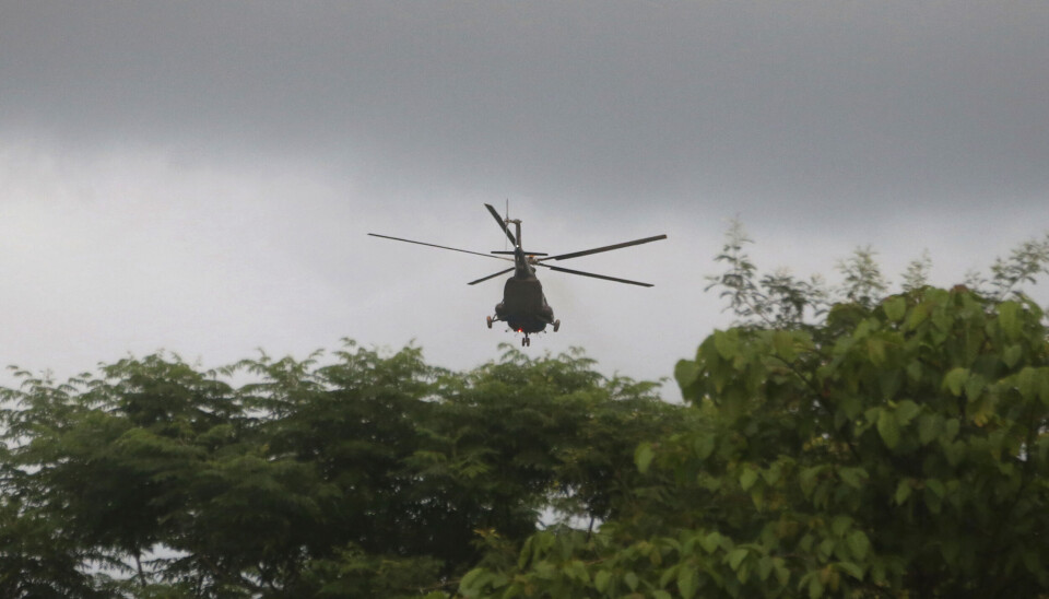 Jakten på den försvunna cylindern pågår över ett stort område. Arkivbild. Helikopter som flyger över gröna träd