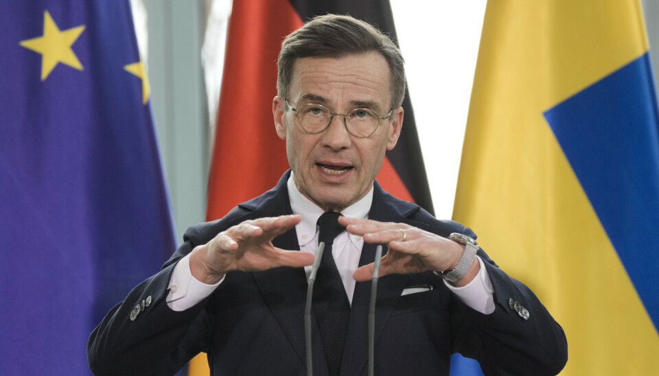 Statsminister Ulf Kristersson (M) i Berlin. Ulf Kristersson talar, i bakgrunden tyska och svenska flaggan