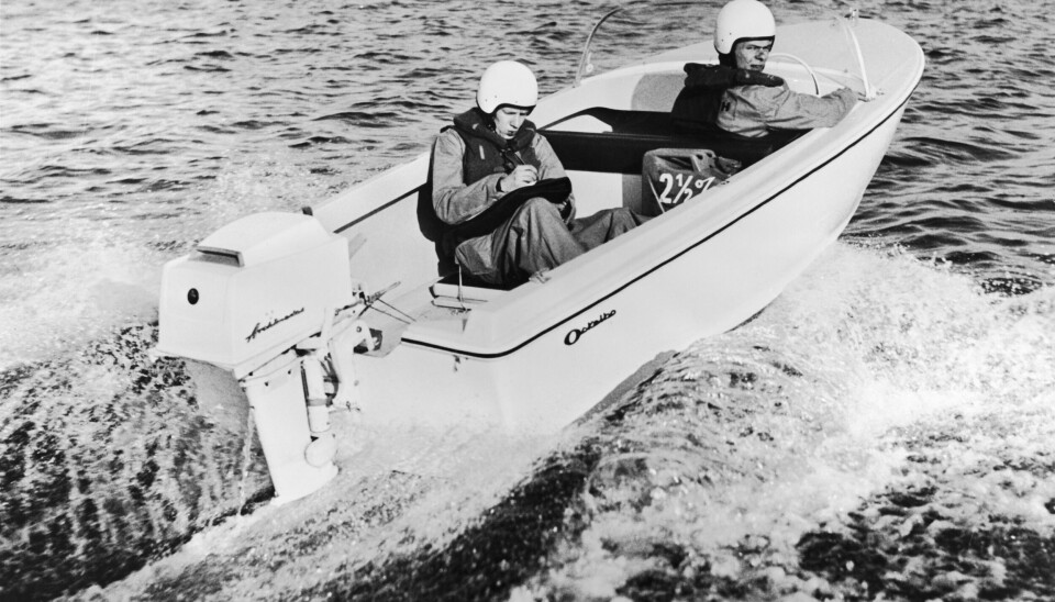 En vit motorbåt av märket Ockelbo som provkörs av två män med hjälmar. Den ena tar anteckningar medan den andra kör.