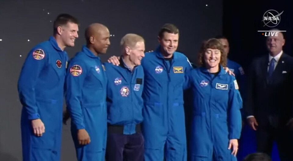 Fyra astronauter och en Nasachef arm i arm på en presskonferens.