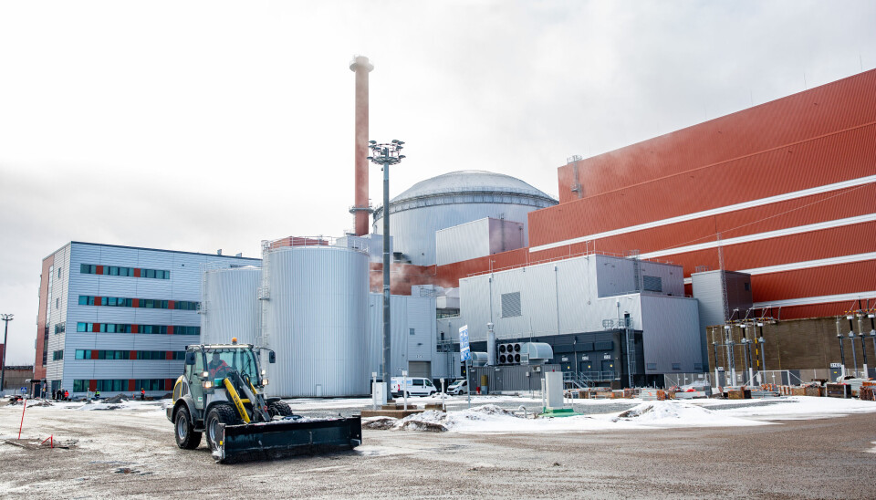 Olkiluoto 3 på finska västkusten. Bilden togs i mars 2023. Reaktorbyggnaden och turbinhallen syns bakom ett arbetsfordon.