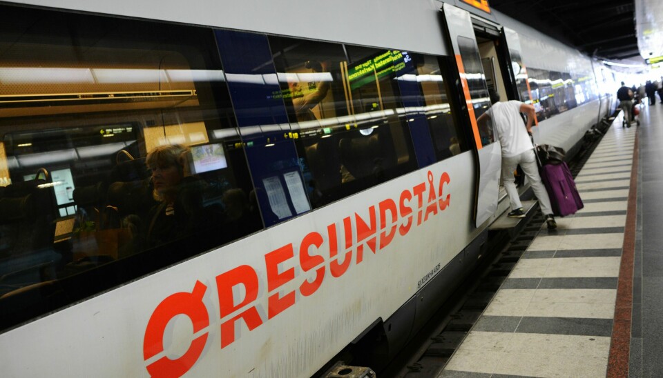 Ett Öresundståg står vid en perrong, resenär i ljusa kläder kliver ombord.