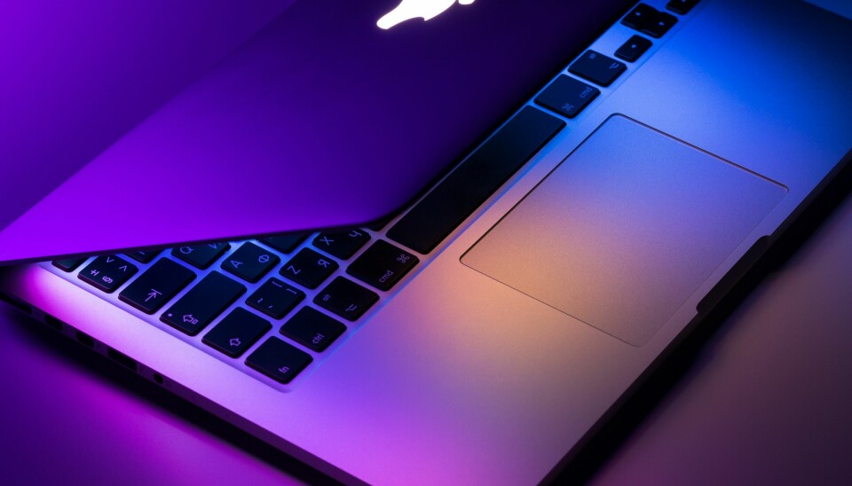En macbook som ligger på ett bord med lila och blå färger