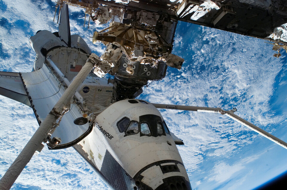 Två robotarmar lastar ur en rymdfärja.
