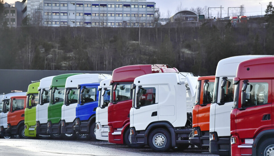 Scania-lastbilar som står på rad. Förarhytter i rött, vitt, blått och grönt