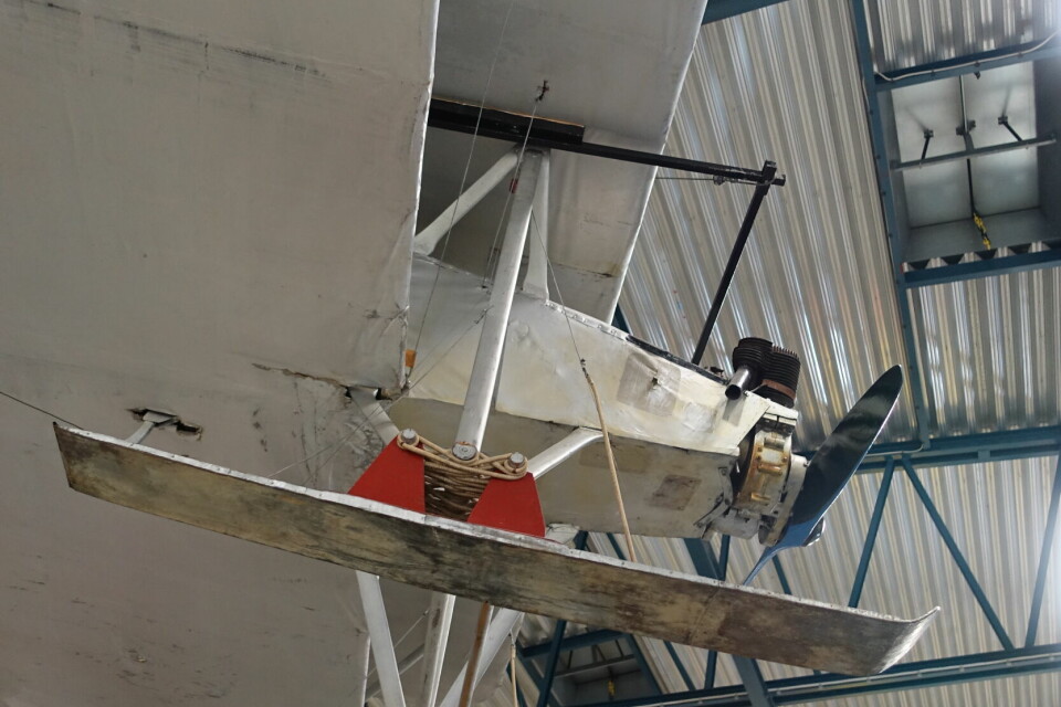 Pappersfokkern upphängd i lagerlokalens tak, med två vingspann och helt byggd av vitt kraftpapper.