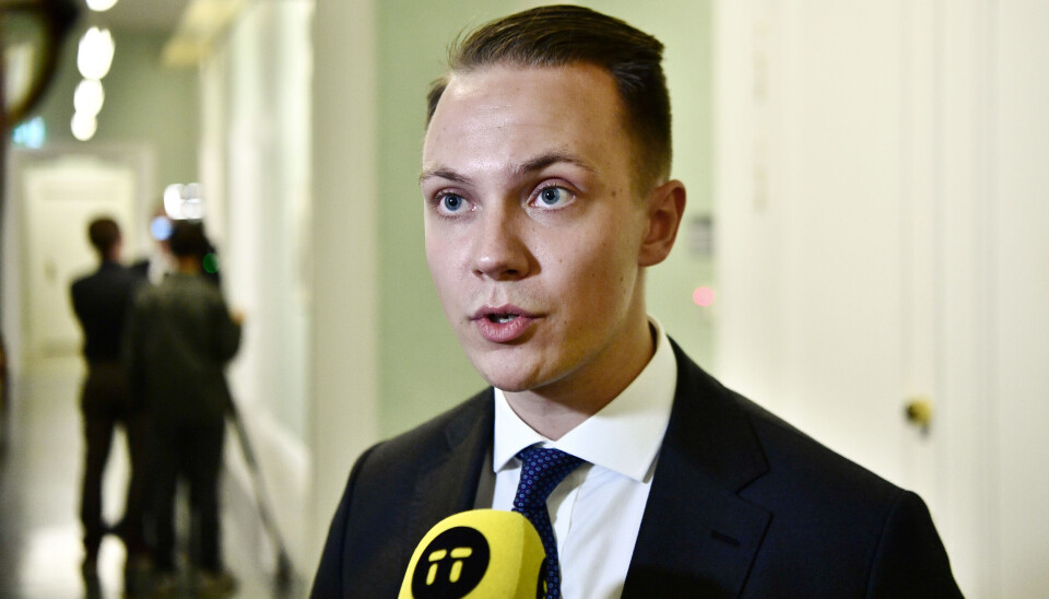 Tobias Andersson (SD) ledamot i riksdagens näringsutskott. Arkivbild. Tobias Andersson, SD, i svart, vit skjorta och svart slips. Han har en gul mikrofon framför sig