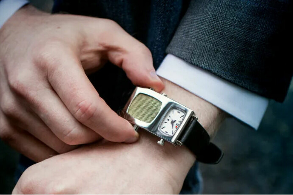 Ett rektangulärt armbandsur med en klassisk klocka och en radio. uret har guldkanter.