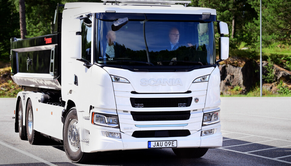 Nu ska ellastbilar kunna massproduceras i Södertälje. En vit lastbild från Scania som kör på asfalt. Bakom vita lastbilen syns grön natur.