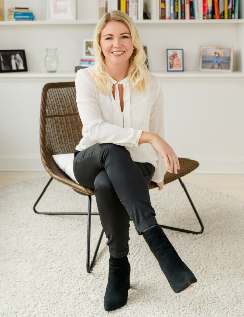 The picture shows Elina Berglund Scherwitz, co-founder and one of two CEOs of Natural Cycles.  Elina is wearing a white top, black pants and is sitting in a chair in her home in New York.