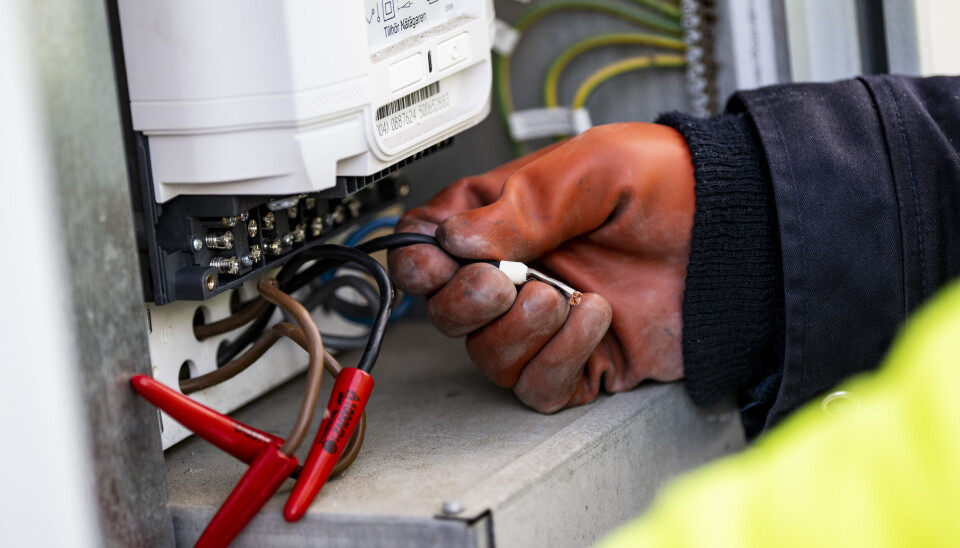 En elektriker monterar ny elmätare. Genrebild. En elektriker med röd handske monterar ny elmätare. På några av sladdarna sitter röda detaljer