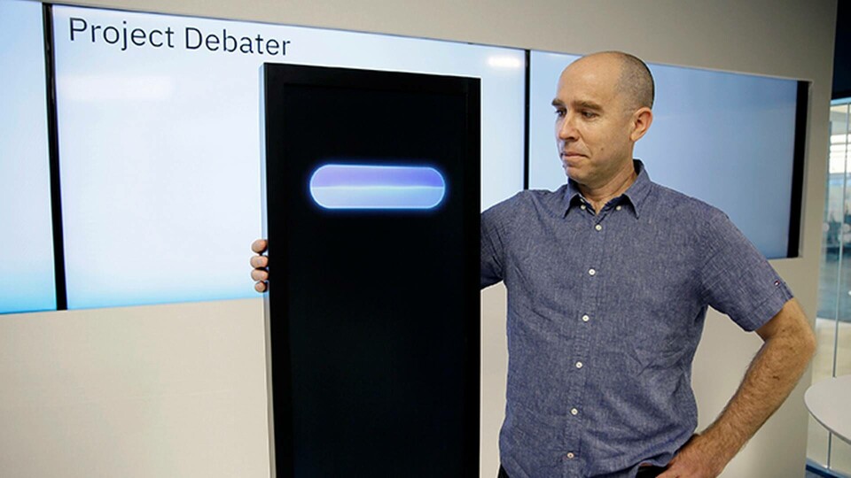 Noam Slonim som arbetar med IBM står bredvid ai:n Project Debater. Foto: AP Photo/Eric Risberg/TT Noam Slonim som arbetar med IBM står bredvid ai:n Project Debater. Foto: AP Photo/Eric Risberg/TT