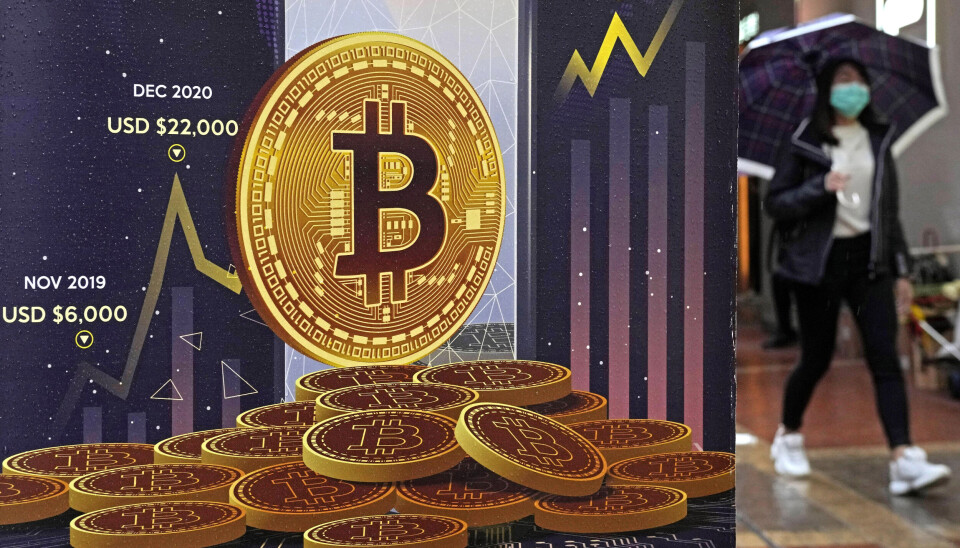 Binance är världens största kryptobörs sett till transaktioner. Arkivbild. Illustration av guldmynt som det sår B på. En kvinna med munskydd och paraply passerar.