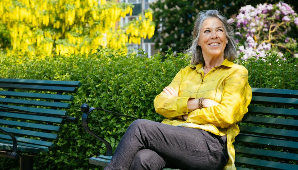 En kvinna i gul skjorta sitter på en bänk.