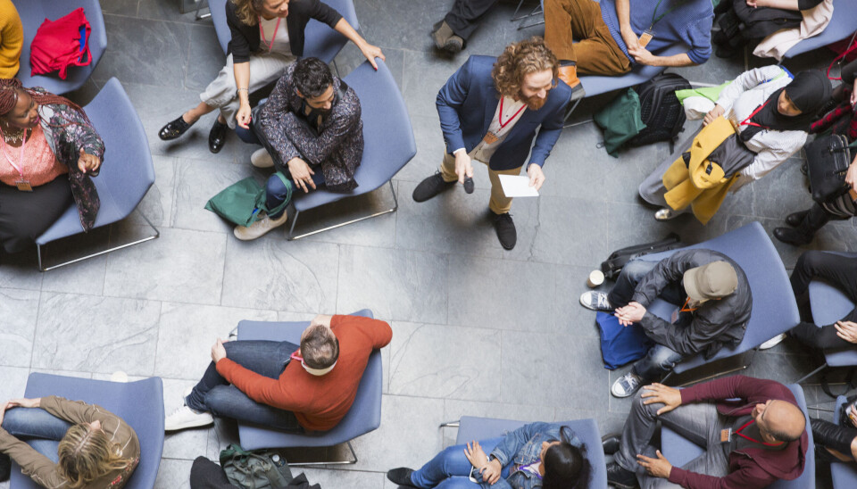 Overhead view conference audience listening to speaker with microphone.