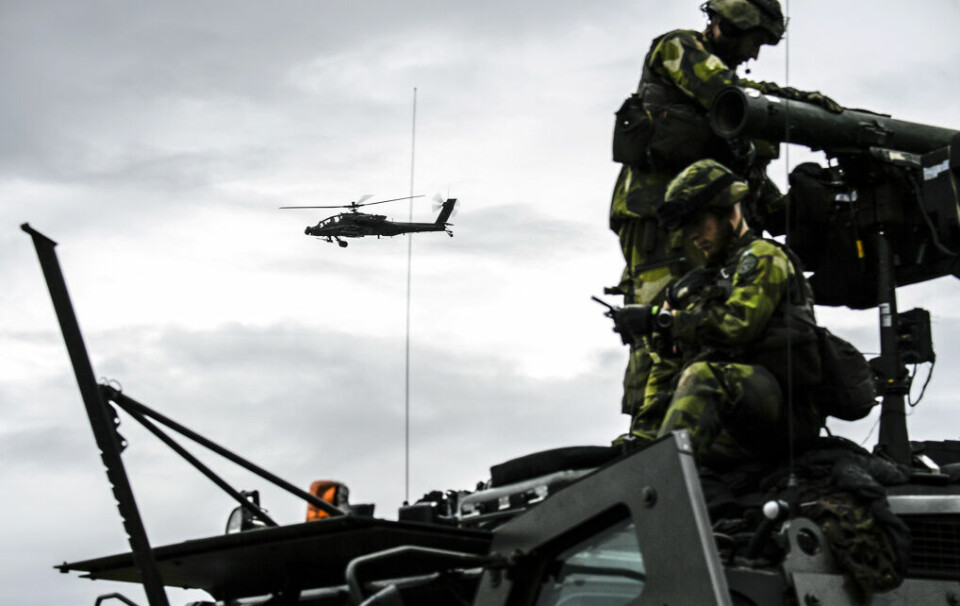 Två militärer på ett fordon, en helikopter i bakgrunden.