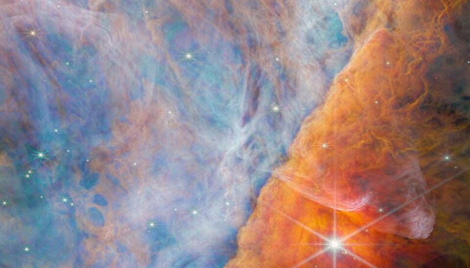 I mitten av Orionnebulosan strålar unga stjärnor i ultraviolett ljus, vilket lyser upp omgivningen på olika sätt. Längs molnbanken ligger ett litet mörkt moln i vilket en ny stjärna och möjligen flera planeter håller på att bli till. I kanten av det lilla molnet lyser det från molekyler av CH3+, vilket visas i gult i den här bilden. Bilden är tagen i infrarött ljus av rymdteleskopet James Webb med kameran NIRCam. I mitten av Orionnebulosan strålar unga stjärnor i ultraviolett ljus, vilket lyser upp omgivningen på olika sätt. Längs molnbanken ligger ett litet mörkt moln i vilket en ny stjärna och möjligen flera planeter håller på att bli till. I kanten av det lilla molnet lyser det från molekyler av CH3+, vilket visas i gult i den här bilden. Bilden är tagen i infrarött ljus av rymdteleskopet James Webb med kameran NIRCam.