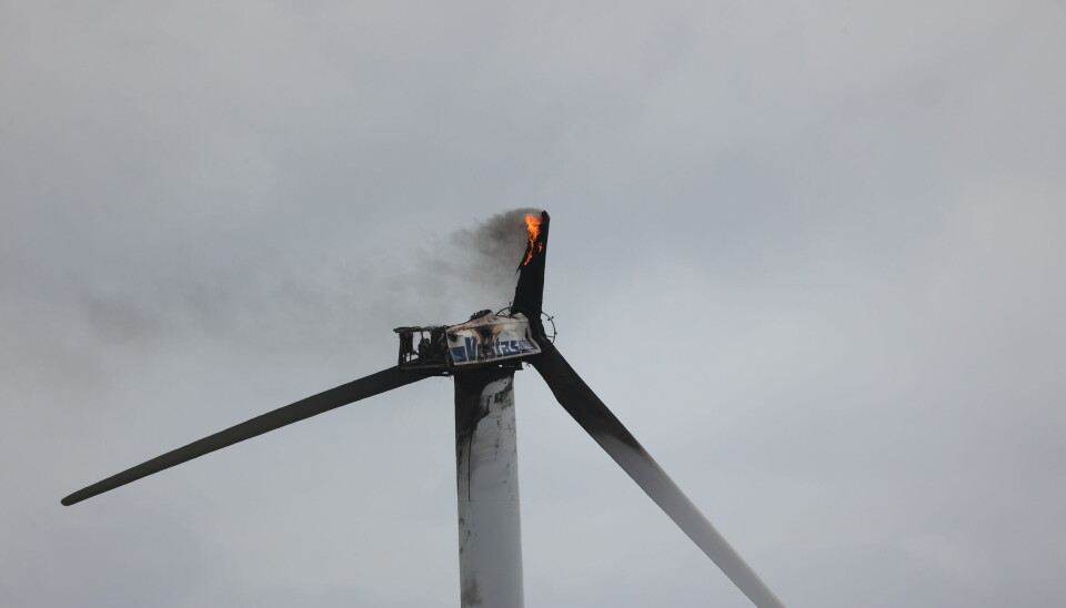 Ett eldhärjat vindkraftverk. Lågor syns på ett av rotorbladen, som delvis har ramlat loss.