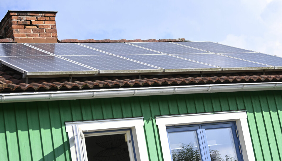 Grönt hus med svarta solpaneler på taket