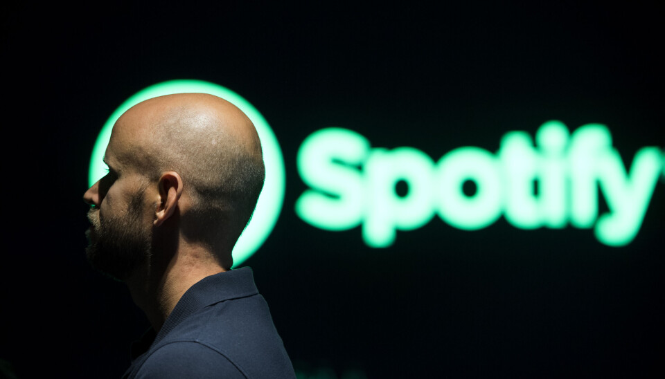Spotify, med grundaren Daniel Ek i förgrunden, utnyttjas av kriminella för pengatvätt, enligt en ny granskning. Arkivbild. Skallig man framför en grön logga som det står Spotify på.