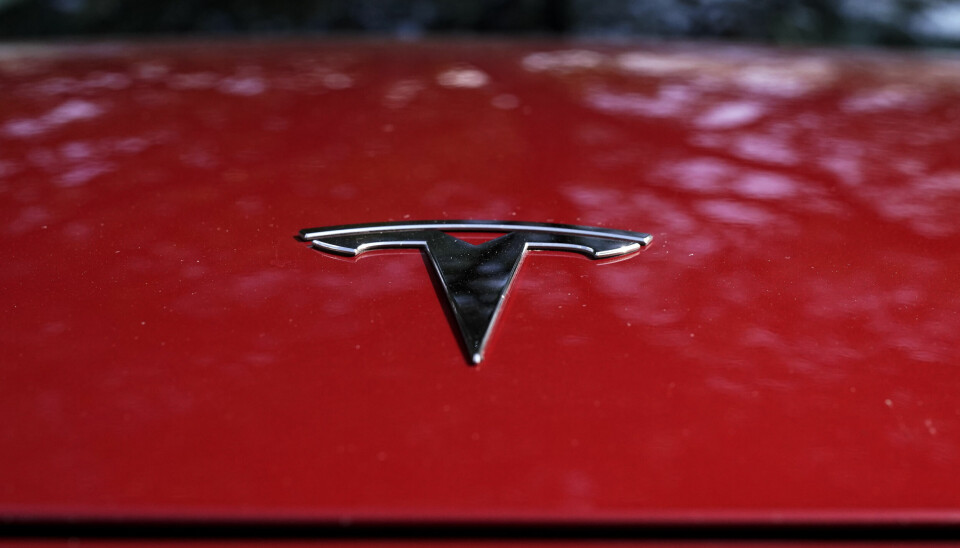 Röd motorhuv med ett grått T på som signalerar Teslas logga.
