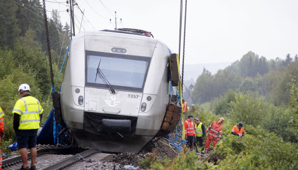 Sommarens skyfall medförde bland annat att banvallen kollapsade utanför Hudiksvall och ett SJ -tåg spårade ur. Arkivbild. Urspårat grått tåg. Framför tåget står en man med vit hjälm och reflexväst.