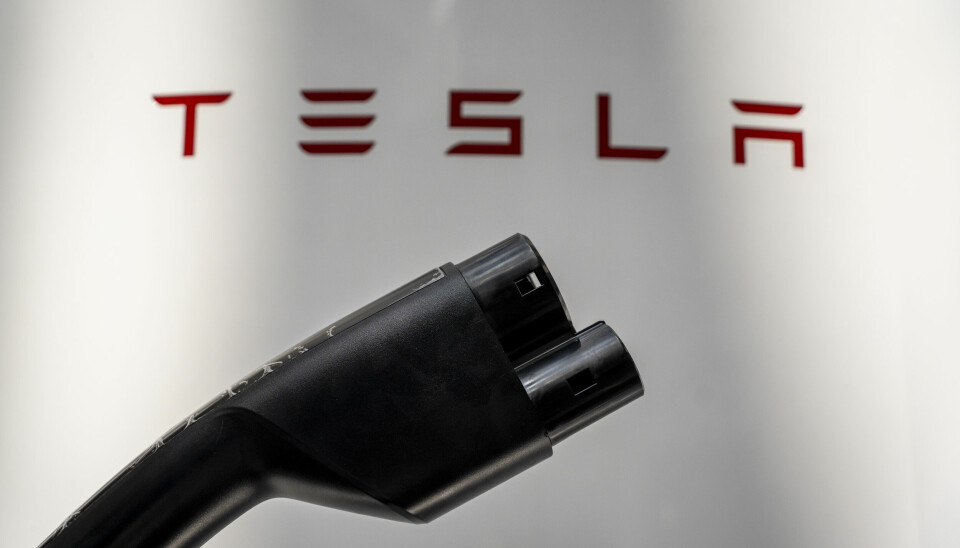 En svart laddare för elbil framför en text där det står Tesla