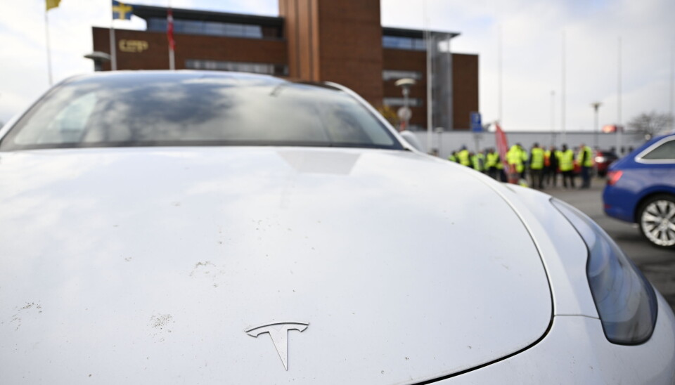 En Teslabil i förgrunden till konfliktande transportarbetare vid Malmö hamn. Arkivbild. En Teslabil i förgrunden till konfliktande transportarbetare vid Malmö hamn. Arkivbild.