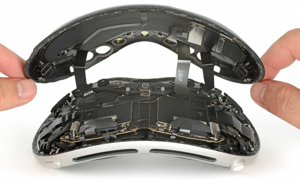 Bilden visar en isärplockad skärm på Apples VR-headset Vision Pro. Två händer kommer in från varsin sida om bilden, och håller i en flera paneler som skärmen utgörs av.