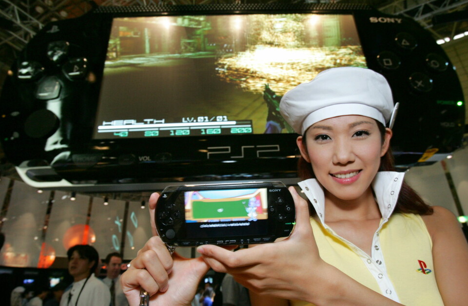 En ung kvinna ler och håller fram en Sony Playstation-konsol