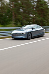 En futuristisk Volkswagen XL1 kör på en väg med skog i bakgrunden.