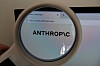 Ett förstoringsglas fokuserar på Anthropics logotyp och webbadress på en datorskärm.
