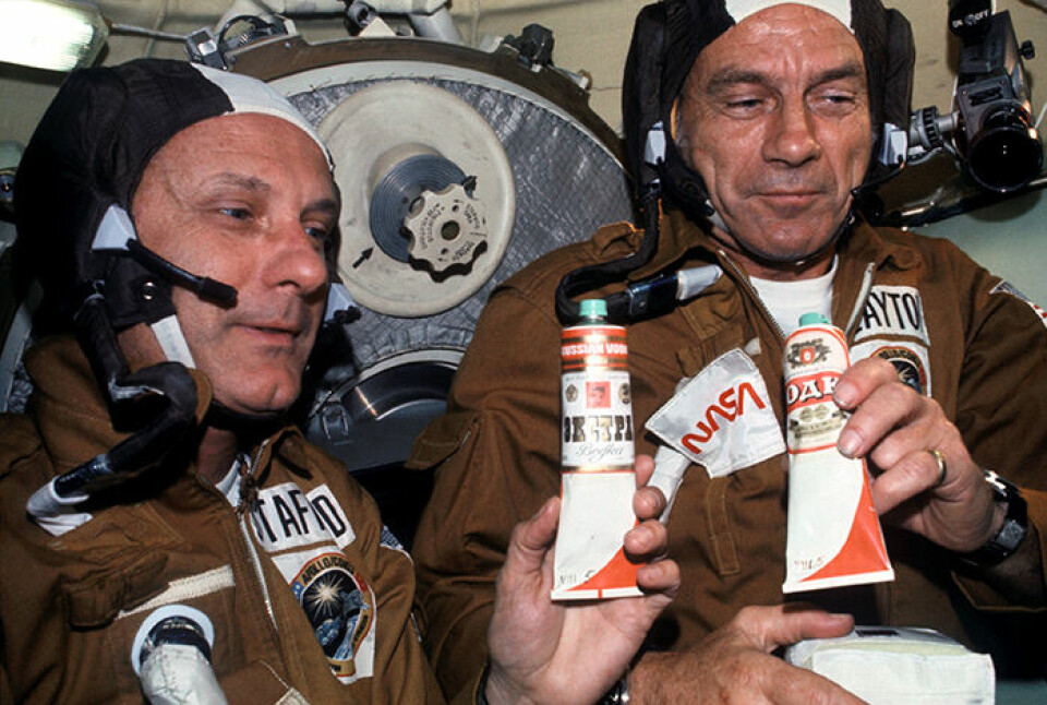 Astronauterna Thomas Stafford och Donald Slayton besöker den sovjetiska Sojuzmodulen och håller i tuber som innehåller borsjtj, rysk rödbetssoppa. Men tuberna har fått nya etiketter märkta ”vodka”. Foto: Nasa