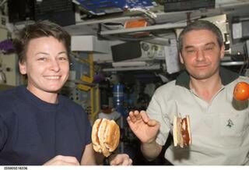 Astronauten Peggy Whitson och kosmonauten Valery Korzun tar sig en hamburgare med tillbehör på Internationella rymdstationen ISS år 2002. Foto: Nasa