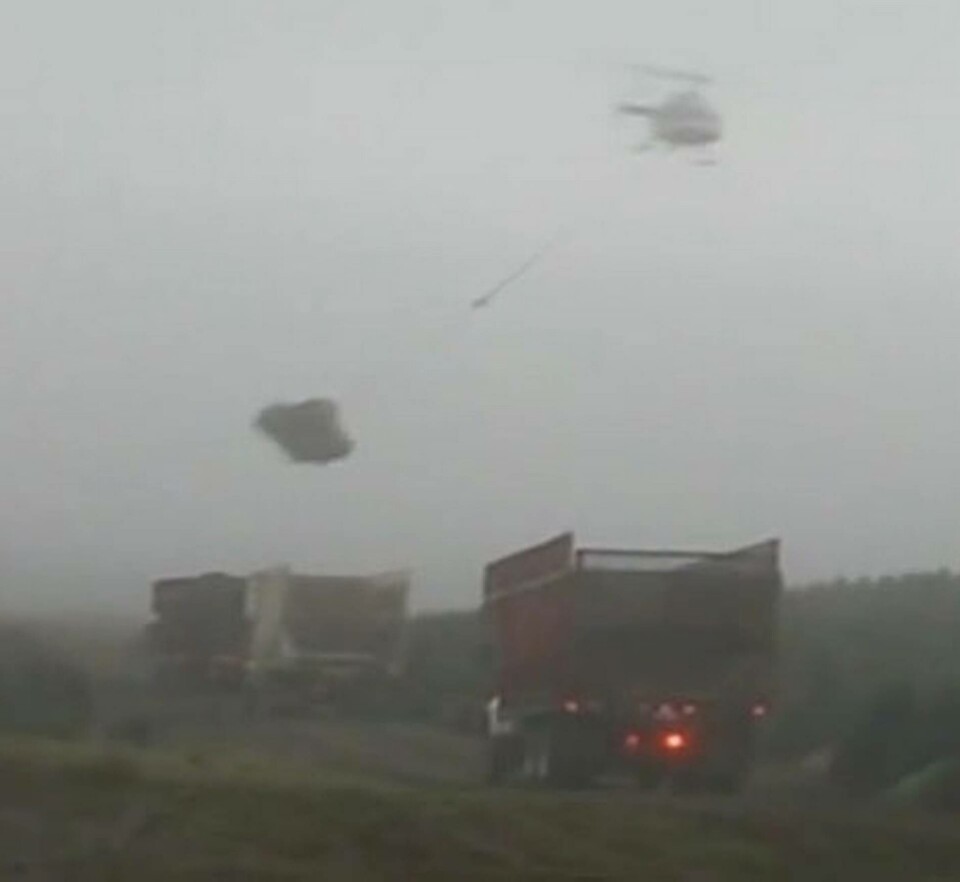 Helikopterpiloten Dan Clark svingar sin granlast mot den väntande lastbilen. Foto: The Northwest Report Helikopterpiloten Dan Clark svingar sin granlast mot den väntande lastbilen. Foto: The Northwest Report