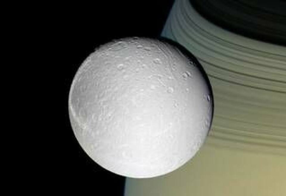 En av Cassinis tidigare bilder av Dione, vars istäckta grå yta avtecknar sig mot Saturnus. Foto: NASA/JPL/Space Science Institute