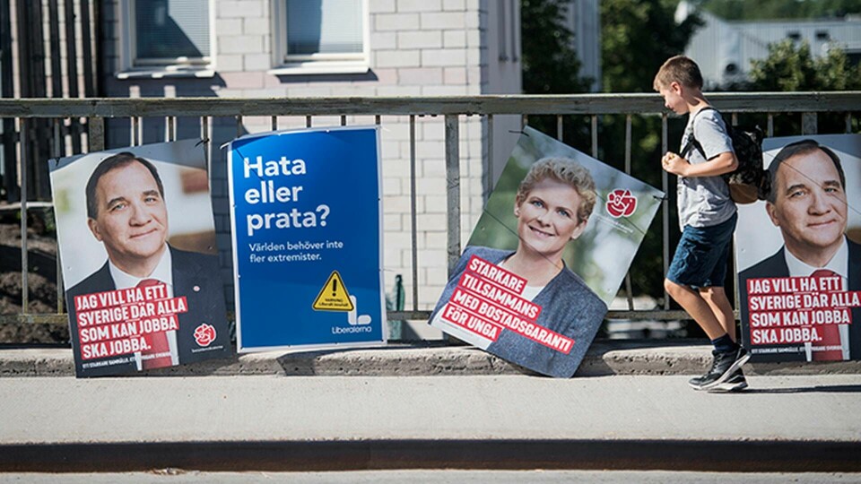 En pojke går förbi valaffischer för Socialdemokraterna och Liberalerna. Foto: Fredrik Sandberg / TT