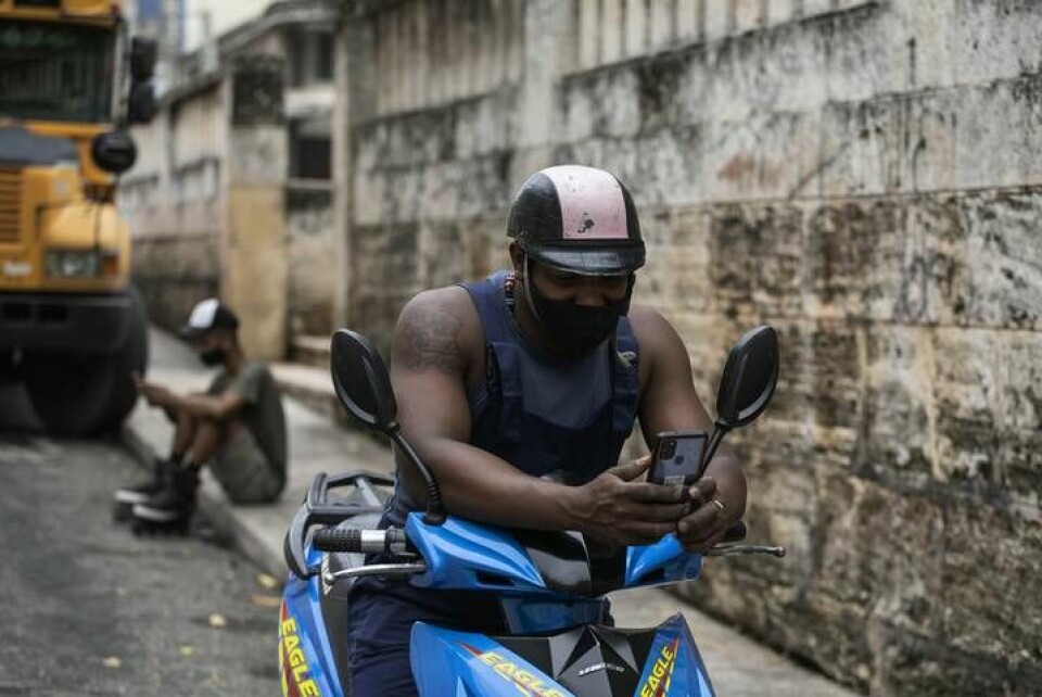 Två män surfar via sina mobiler i närheten av en park i Havanna som erbjuder uppkoppling via trådlöst nätverk. Foto: Eliana Aponte/AP/TT
