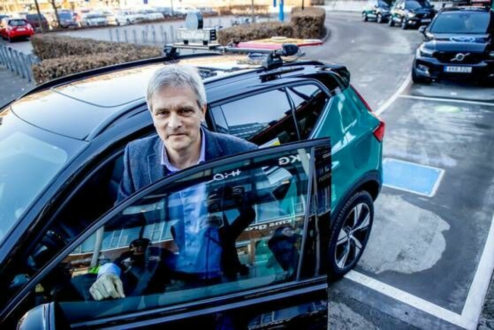 Robert Eriksson på Volvo Cars vid en taxi som just kört av den blå, kvadratiska laddplattan. Hittills finns tekniken med trådlös laddning inte i Volvos vanliga, eldrivna personbilar. Men om några år kan det vara dags. Foto: Adam Ihse/TT
