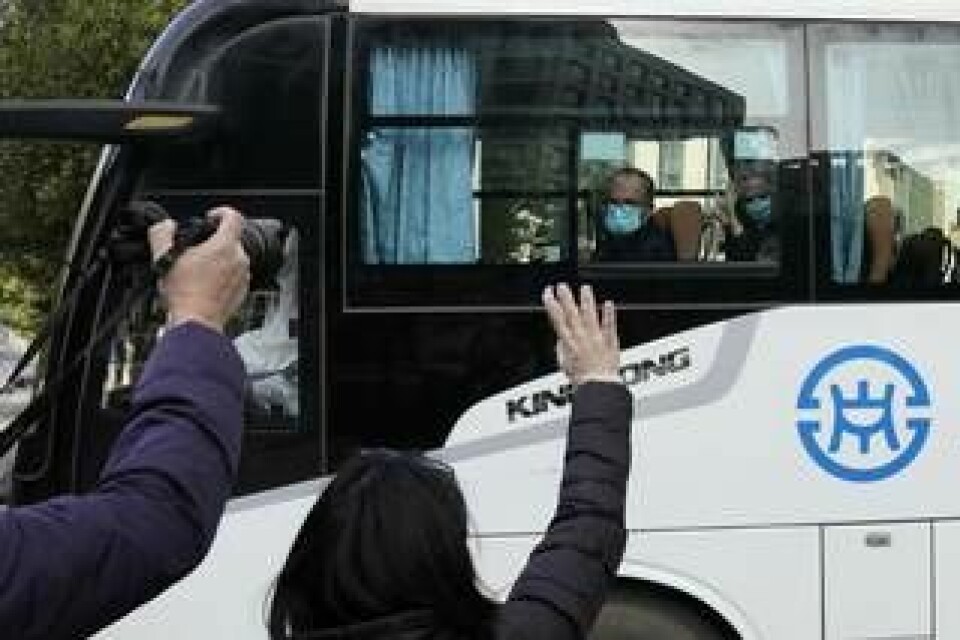 Människor vinkar till WHO:s experter som nu har fått lämna karantänhotellet i Wuhan. Foto: Ng Han Guan/AP/TT