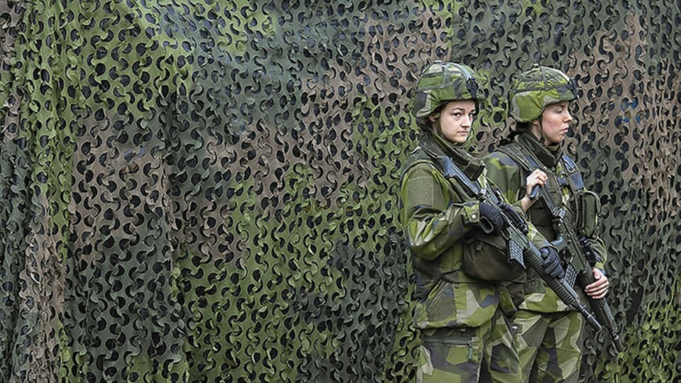 Militärfordon med skyddsnät vaktas av två soldater under försvarsövningen Aurora 17. Foto: Jonas Ekströmer / TT